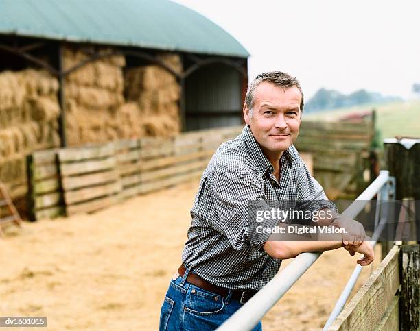 famer leaning on a gate in a paddock on a farm - agriculteur local photos et images de collection