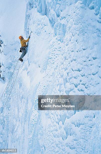 man climbing up a snow covered rock face using crampons and an ice pick - peter snow stock pictures, royalty-free photos & images