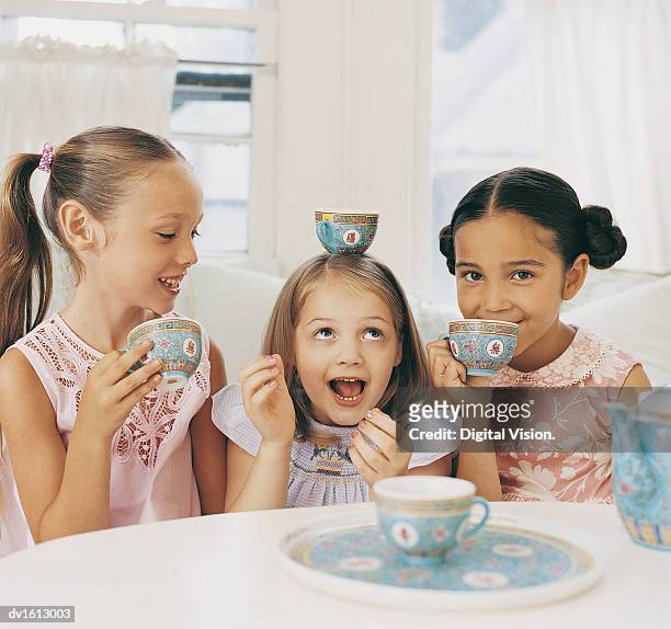 three girls sitting side by side having a tea party and making fun - tea party fotografías e imágenes de stock