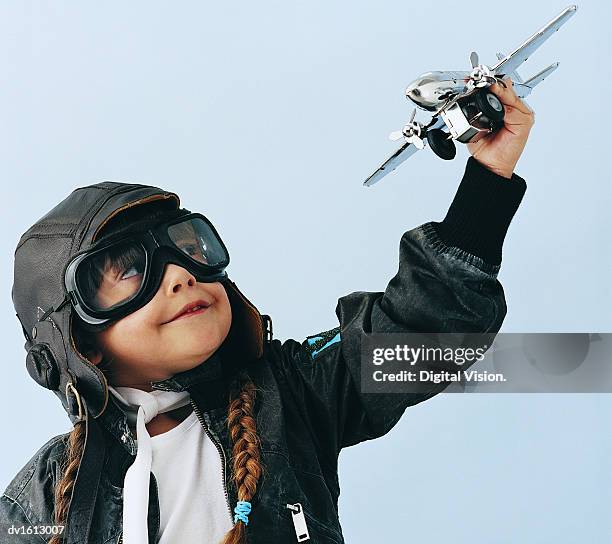 young girl in an aviator costume playing with a toy aircraft - gender role - fotografias e filmes do acervo