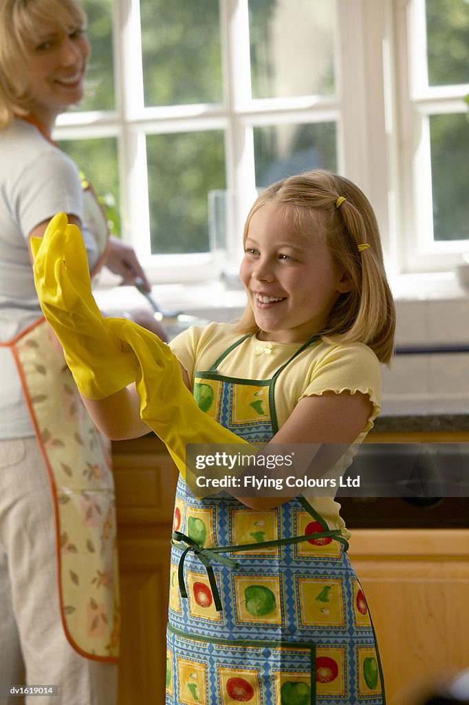 Daughter Adjusting Rubber Gloves While her Mother Washes Up