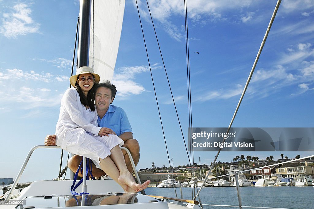 Smiling Couple Sit Together on the Deck of a Sailing Boat