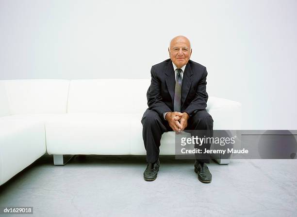 portrait of a senior man sitting on a sofa - man waiting couch stock pictures, royalty-free photos & images