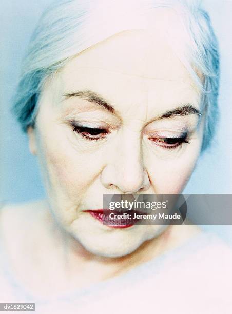 studio portrait of an elderly woman, her eyes looking down - down blouse stockfoto's en -beelden