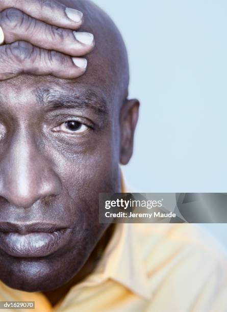 portrait of a mature man wearing a yellow shirt with a hand on his head looking depressed - hand on head foto e immagini stock