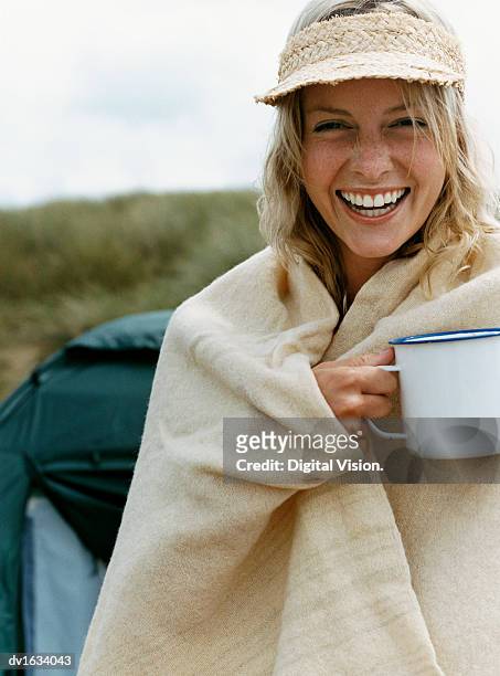 laughing woman outdoors wrapped in a blanket and holding a mug - oberkörper happy sommersprossen stock-fotos und bilder