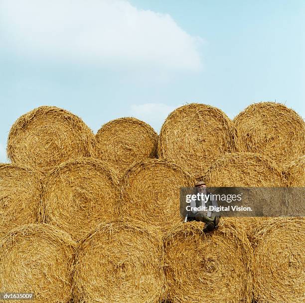 farmer relaxing on hay bales, looking at the camera - heuballen stock-fotos und bilder