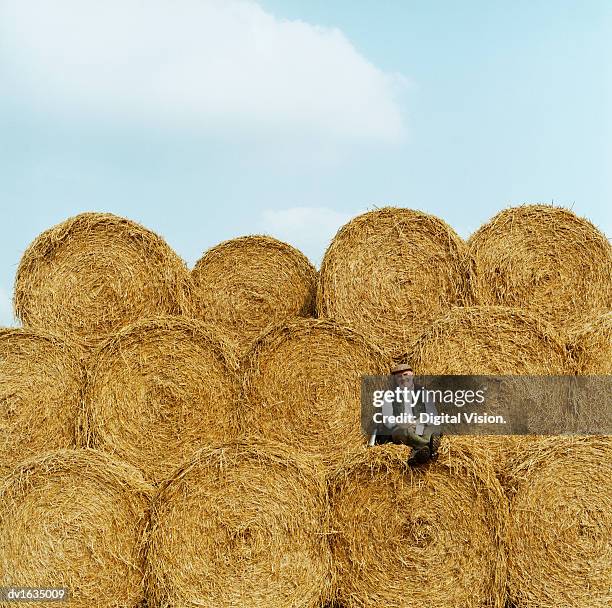 farmer relaxing on hay bales, looking at the camera - a balze fotografías e imágenes de stock
