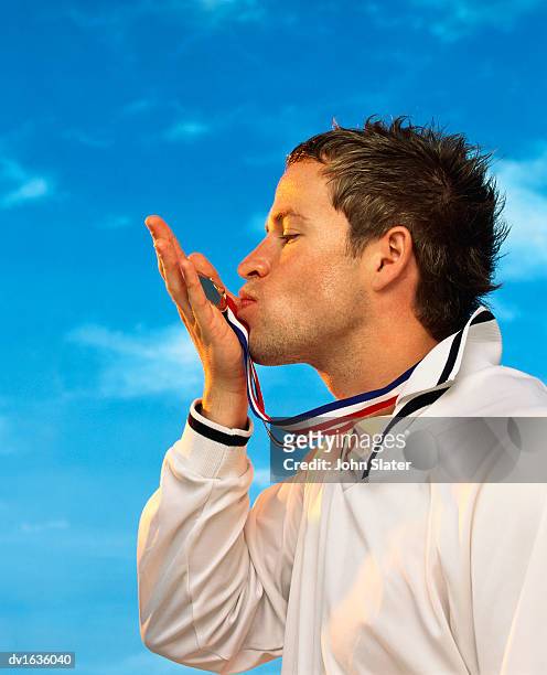 profile portrait of an athlete kissing his gold medal - tracksuit top stock pictures, royalty-free photos & images