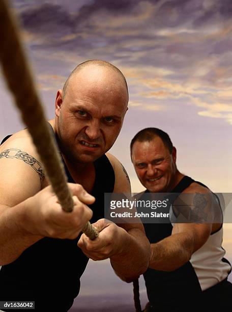 two men pulling on the end of a rope in a tug of war - war stock-fotos und bilder