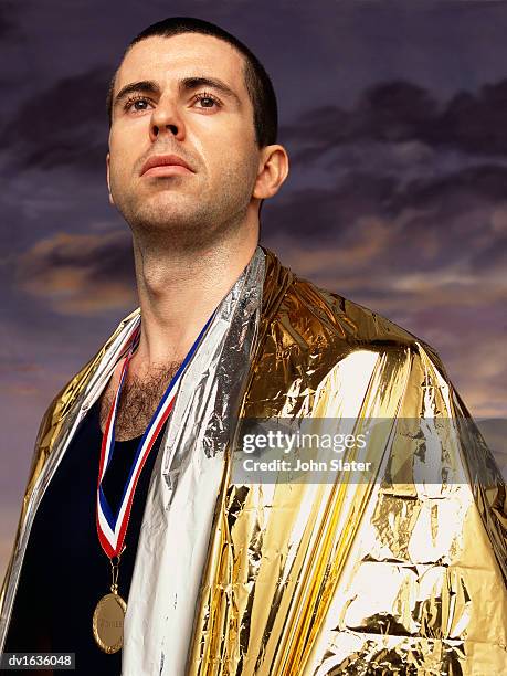 portrait of a male athlete wearing a gold medal and a golden foil blanket - emergency equipment 個照片及圖片檔