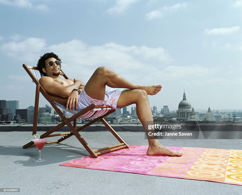 Man Relaxing in a Deck Chair on a Roof Against a London Skyline