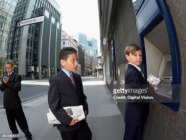 three young boys dressed as businessmen wait in line to withdraw money from a hole-in-the-wall, city of london - vigils are held for the victims of the london bridge terror attacks stockfoto's en -beelden
