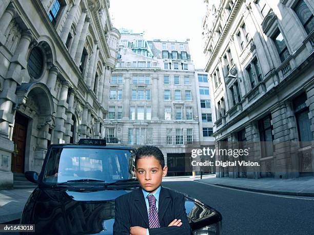 boy dressed as a businessman standing in a road with a taxi behind him - renversement des rôles photos et images de collection