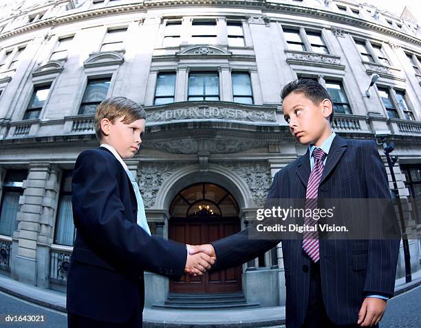 two boys dressed as businessman shaking hands - renversement des rôles photos et images de collection