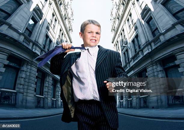 boy dressed as a businessman looking stressed and removing his tie - renversement des rôles photos et images de collection