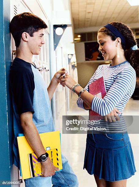 teenage boy and girl stand face to face by lockers in a secondary school corridor, flirting - secondary stock pictures, royalty-free photos & images