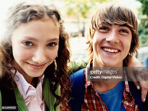 teenage girl stands smiling with her arm around her friend - casal adolescente imagens e fotografias de stock
