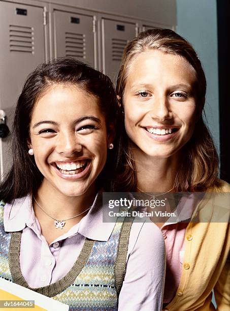 portrait of two smiling students, with lockers in the background - solo adolescenti femmine foto e immagini stock