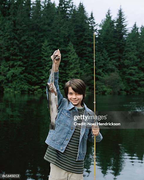 Young Boy Stands By A Lake Holding Up A Fish He Has Caught And A Fishing Rod  High-Res Stock Photo - Getty Images