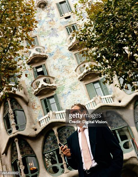 businessman stands in front of casa batllo using his mobile phone, barcelona, spain - casa stock pictures, royalty-free photos & images
