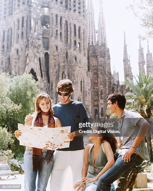 two young couples read a map in front of the sagrada familia, barcelona - familia stockfoto's en -beelden