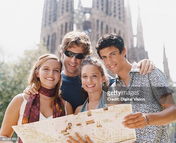four young people stand holding a map in front of the sagrada familia, barcelona - familia stockfoto's en -beelden