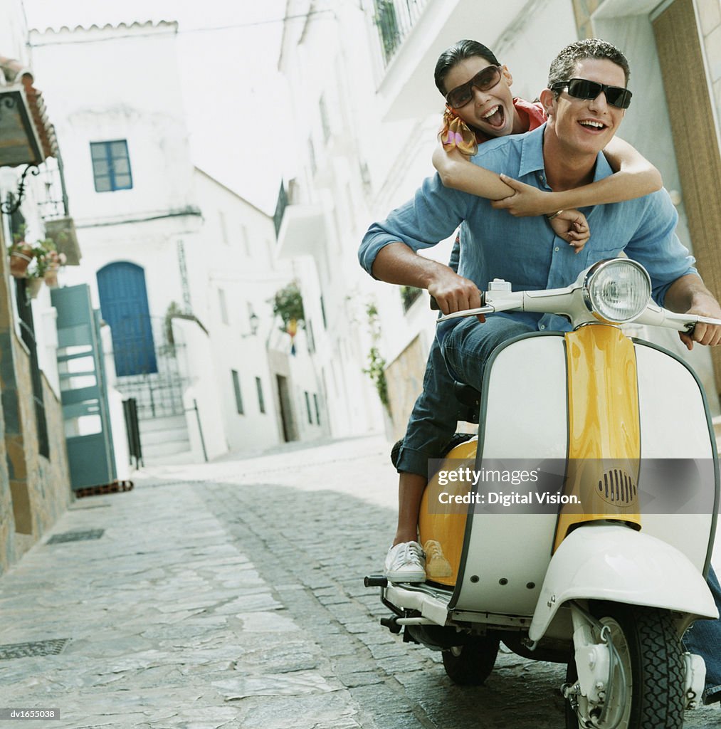 Couple Having Fun Riding on a Motor Scooter Through an Alley