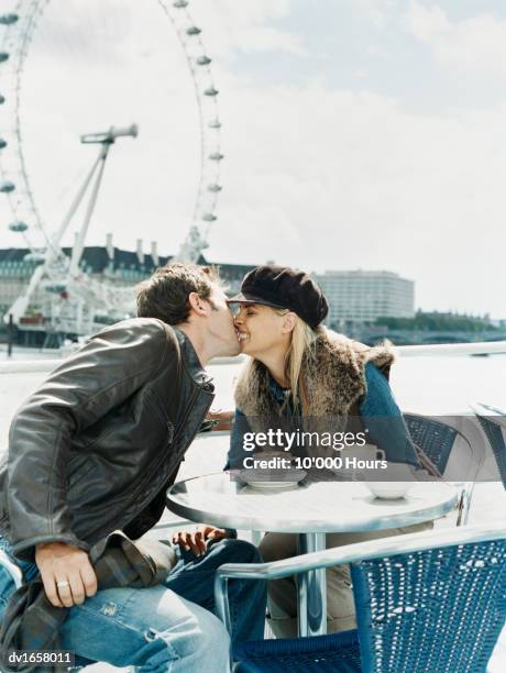 man leaning over to kiss a smiling woman at a cafe ont he thames near the millennium wheel, london - vigils are held for the victims of the london bridge terror attacks stockfoto's en -beelden