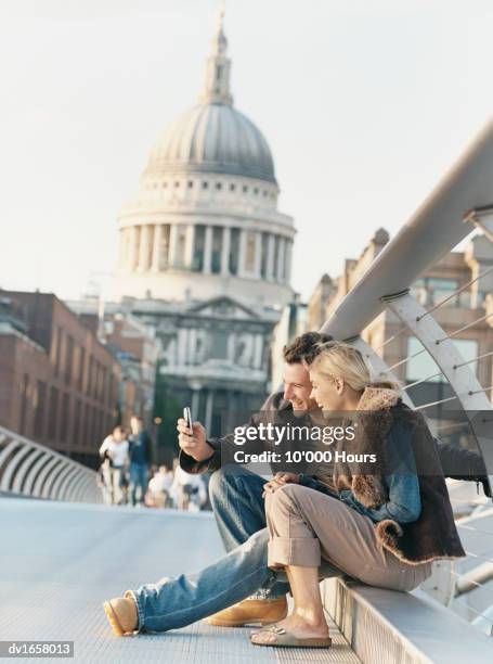 couple using a video phone to photograph themselves on the millenium bridge with st pauls cathedral in the background - st pauls cathedral london - fotografias e filmes do acervo