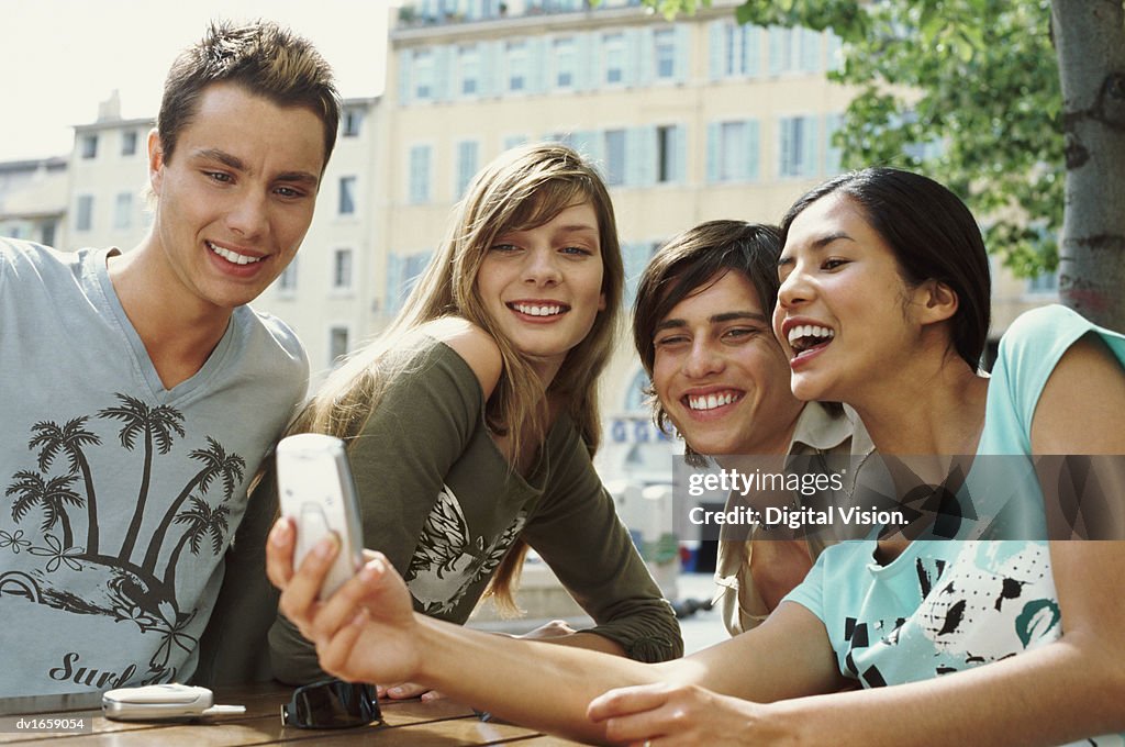 Four Teens Sitting at a Table and Using a Videophone