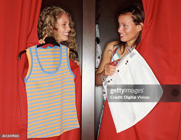 two teenage women standing in changing rooms comparing clothes - close-curtains stockfoto's en -beelden
