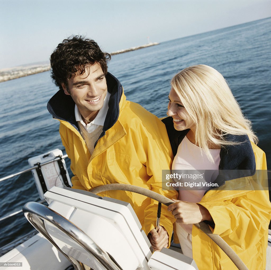 Young Couple Stand at the Helm of a Sailboat, Holding the Ship's Wheel