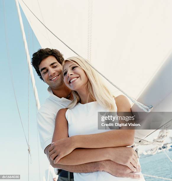 couple stand embracing on the deck of a yacht, looking at the view - sleeveless top stock pictures, royalty-free photos & images