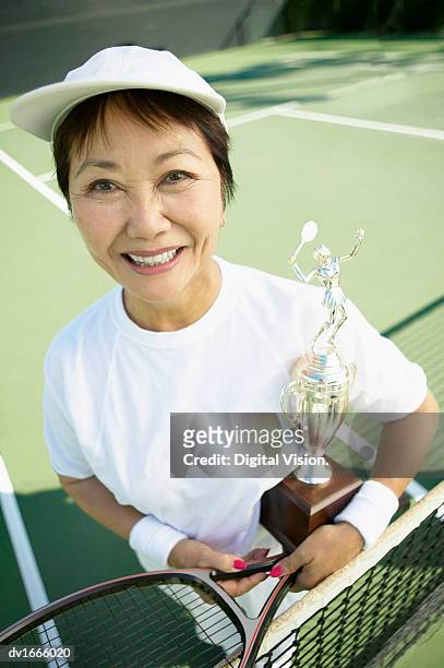 portrait of a woman standing on a tennis court holding a trophy - tennis court stock pictures, royalty-free photos & images