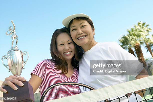 mother and daughter on a tennis court, with the daughter holding a trophy - tennis court stock pictures, royalty-free photos & images