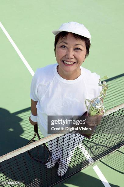 portrait of a woman holding a trophy on a tennis court - tennis court stock pictures, royalty-free photos & images