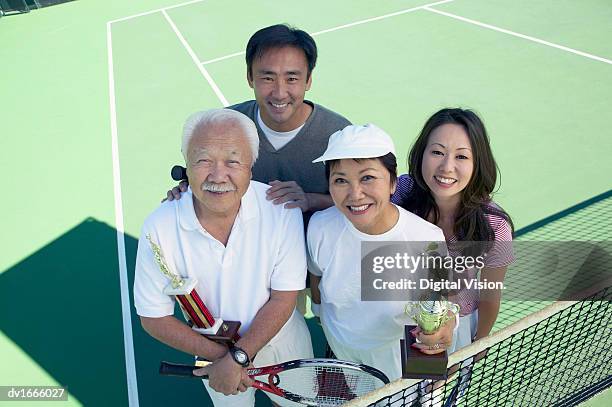 portrait of a senior couple and young couple standing on a tennis court - tennis court stock pictures, royalty-free photos & images