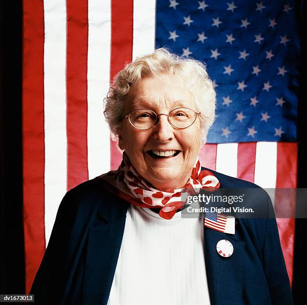 portrait of a senior woman in front of stars and stripes flags - front national leader marine le pen casts vote in first round of french presidential election stockfoto's en -beelden