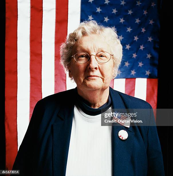 portrait of a senior woman in front of stars and stripes flags - front national leader marine le pen casts vote in first round of french presidential election stockfoto's en -beelden