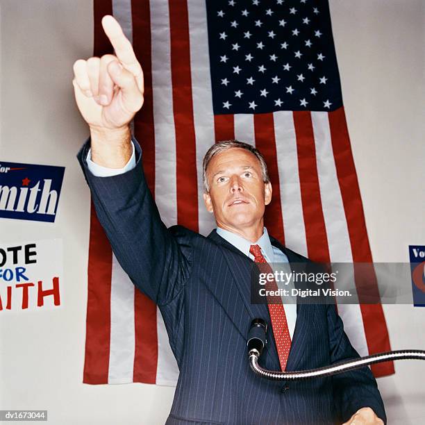 male politician standing in front of a stars and stripes flag giving a speech - republican presidential nominee donald trump holds rally in new hampshire on eve of election stockfoto's en -beelden