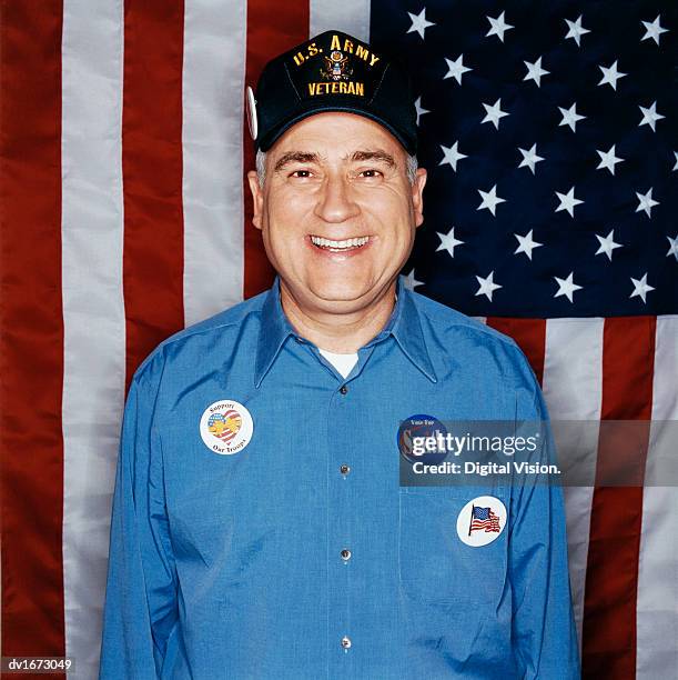 portrait of a mature male veteran standing in front of a stars and stripes flag wearing election badges - republican presidential nominee donald trump holds rally in new hampshire on eve of election stockfoto's en -beelden