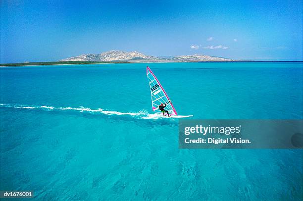 adult windsurfing in the sea off the coast of sardinia, italy - wind surfing stock pictures, royalty-free photos & images