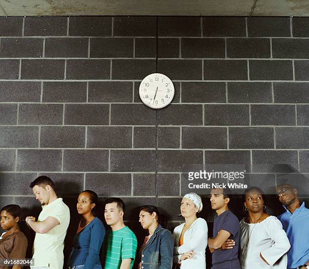 group of students queuing against a brick wall - lining up stock-fotos und bilder