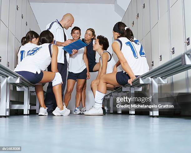 ground level view of a volleyball team listening to their coach in a changing room - locker room ストックフォトと画像