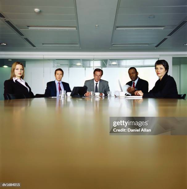 five business people sitting at the far end of a table in a conference room - serious interview stock pictures, royalty-free photos & images