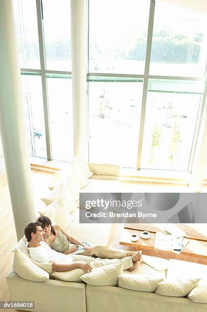 couple relaxing on a sofa in an apartment - brendan stock-fotos und bilder