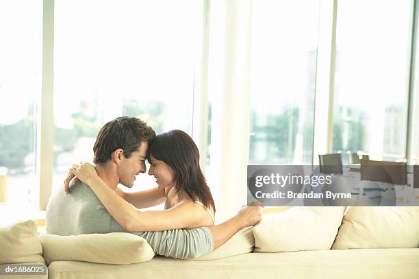 loving couple sitting on a sofa face to face - brendan stock-fotos und bilder
