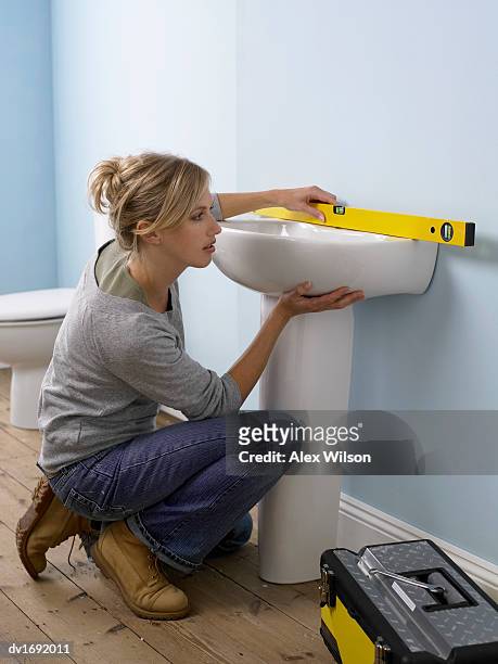 woman using a spirit level on a sink in a domestic bathroom - installation of memorial honors victims of ghost ship fire in oakland stockfoto's en -beelden