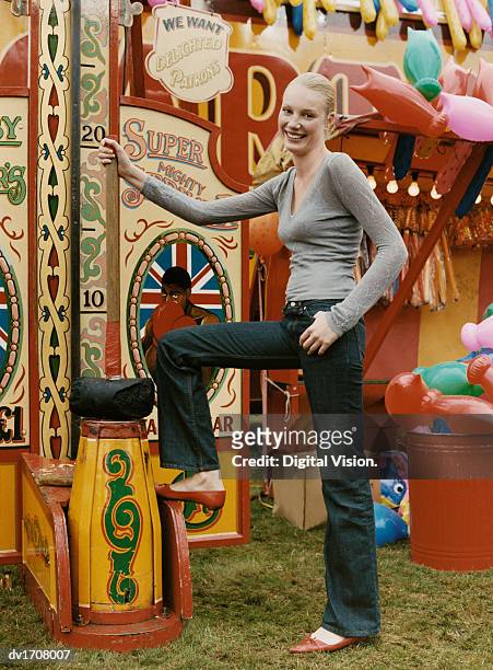 woman posing at an old fashioned fairground strength game, holding a large mallet - strength tester stock pictures, royalty-free photos & images